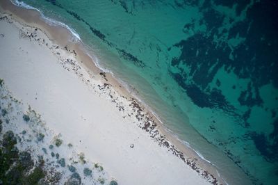 Drone field of view of of footprints in the sand and water from above beach in western australia.