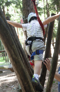 Full length of boy climbing on tree trunk
