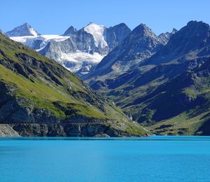 Scenic view of lake and mountains against clear blue sky