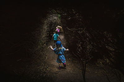 Rear view of siblings running on footpath covered with trees