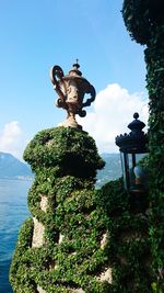 Statue by tree against sky