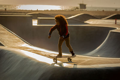 Full length of young woman with skateboard standing against sky