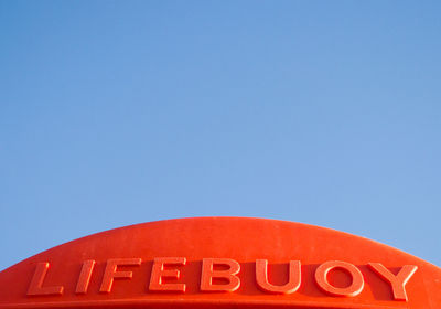 Low angle view of illuminated text against clear blue sky