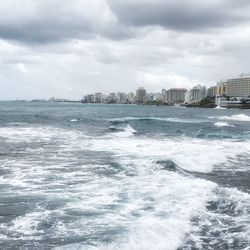 City by sea against cloudy sky