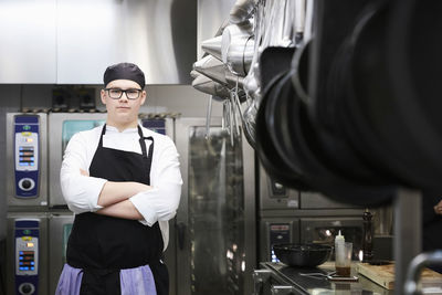 Portrait of male chef student standing arms crossed in commercial kitchen