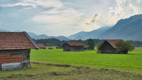 Houses on field by buildings against sky