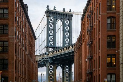 Low angle view of bridge against buildings in city