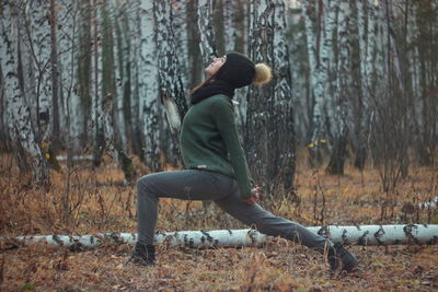 Young woman stretching standing against trees in forest