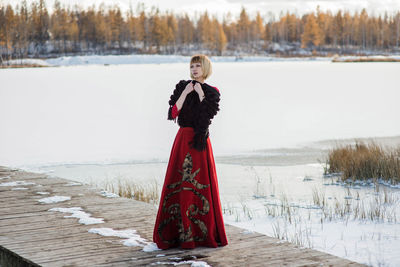 Young woman standing by frozen lake