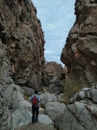 Rear view of woman standing on rock against mountain