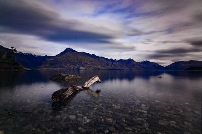 Man on lake by mountains against sky