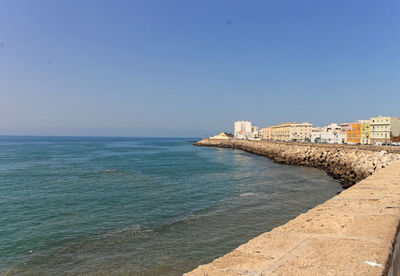 Scenic view of sea in front of city against sky