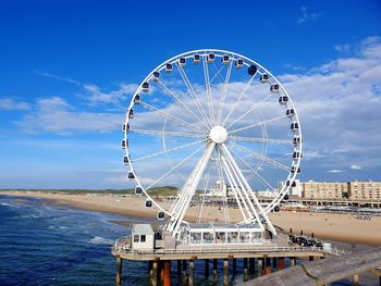 Ferris wheel in city against cloudy sky 