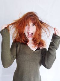 Portrait of woman with arms raised against white background