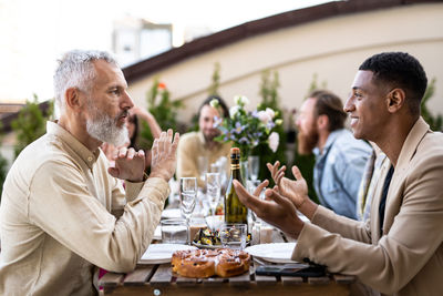 Side view of friends toasting drinks at restaurant