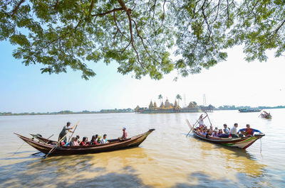 People on boat in sea against sky