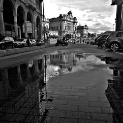 Reflection of buildings in puddle on street