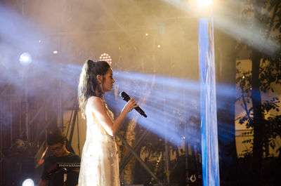 Woman with arms raised standing at music concert