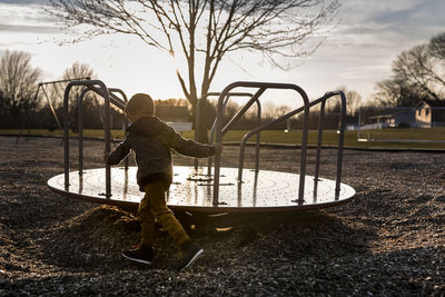 Boy spinning merry-go-round at playground