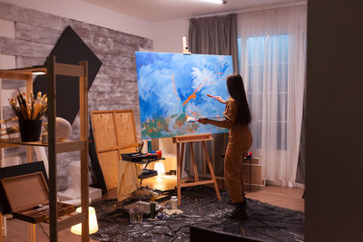 Woman standing by painting at home
