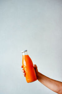 Person holding glass bottle against white background