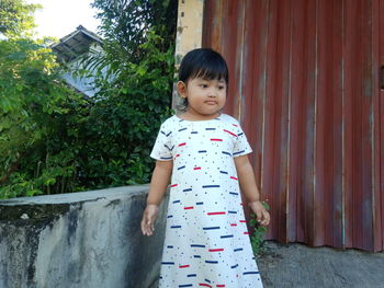 Portrait of cute girl standing against building