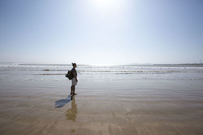 Full length of woman walking on beach against clear sky