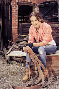 Portrait of mid adult woman sitting on bench against building