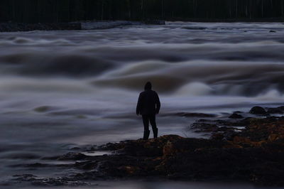 Rear view of man standing on rock at beach