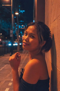 Portrait of smiling woman standing in city at night