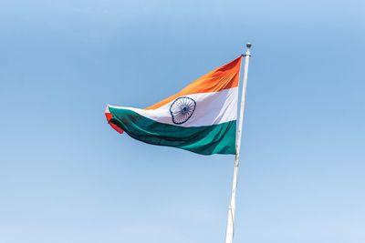 Low angle view of flag against clear blue sky