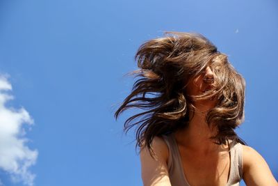 Low angle portrait of woman against blue sky