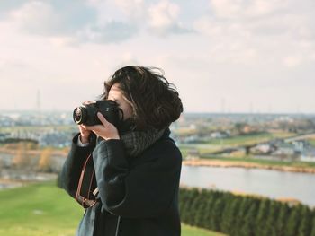 Woman photographing from camera against sky