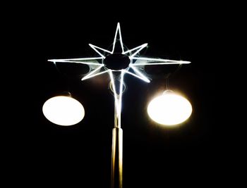 Low angle view of illuminated lighting equipment against black background