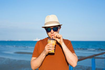 Man holding sunglasses in sea against sky