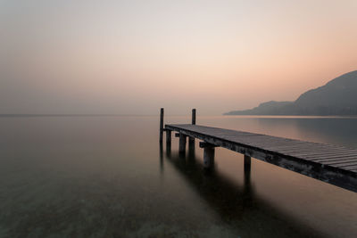 Pier over sea against sky during sunset