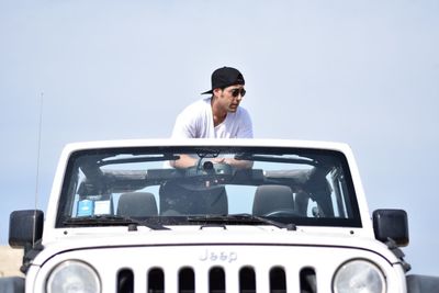 Young man driving car against clear sky