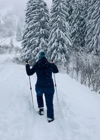 Rear view of woman on snow covered mountain snowshoeing 