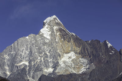 Low angle view of snowcapped mountain against blue sky