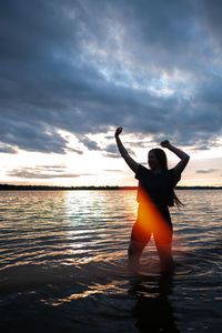 Woman standing at beach against sky during sunset