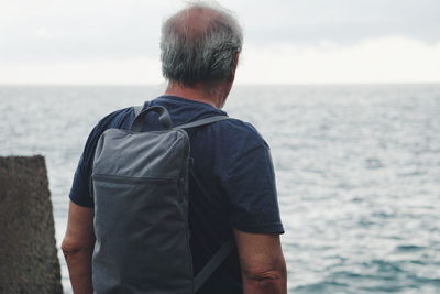 Rear view of man standing against sea