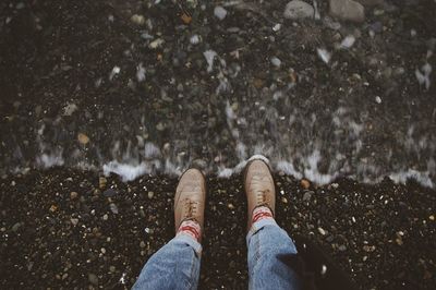 Low section of person standing by stream