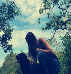 Low angle view of woman with dog against sky