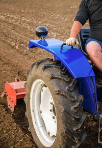 The tractor is cultivating the soil in the farm field. loosening and mixing. 