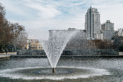 Fountain in city against sky