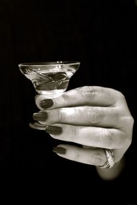 Close-up of hand holding glass over white background