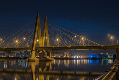 Illuminated bridge over river against sky at night