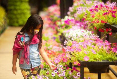 Girl wearing mask looking at flowers in greenhouse
