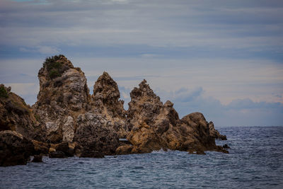 Rock formation in sea against sky