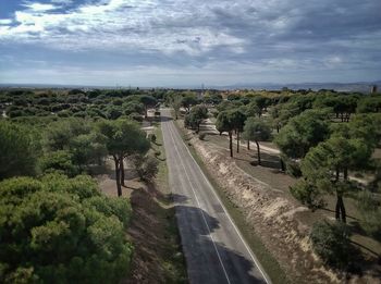 Road amidst trees and landscape against sky